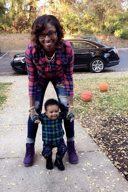 Javourya and her son play in their front lawn. Two basketballs are in the background.